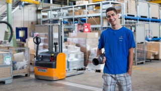 Ein Auszubildender für Lagerlogistik steht vor den Regalen im Lager